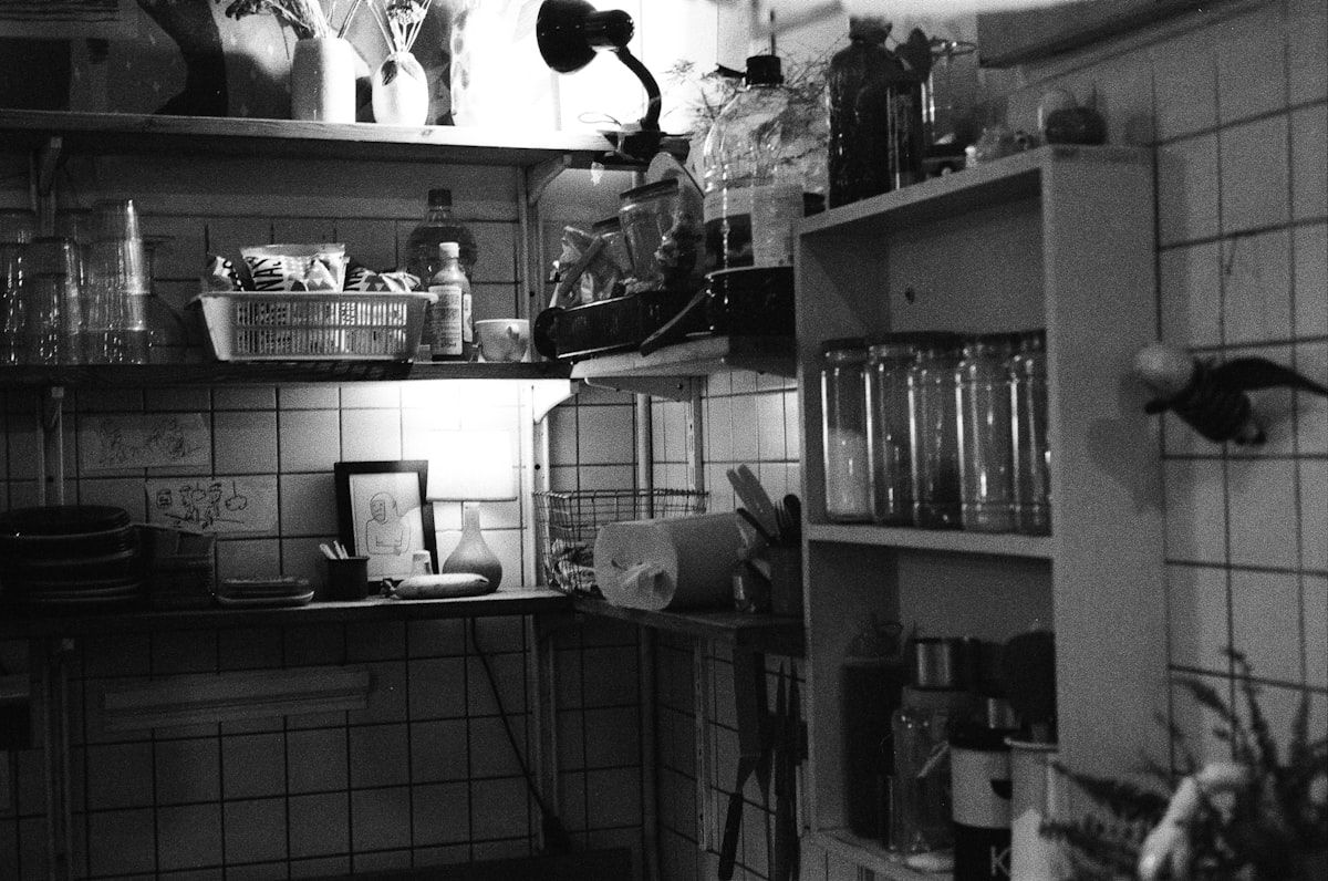 A cramped reach-in closet with one upper shelf and a single hanging rod, showing wasted empty space above the clothes, a few bins crowded on the floor, and mismatched organizers making the storage area feel cluttered and inefficient.