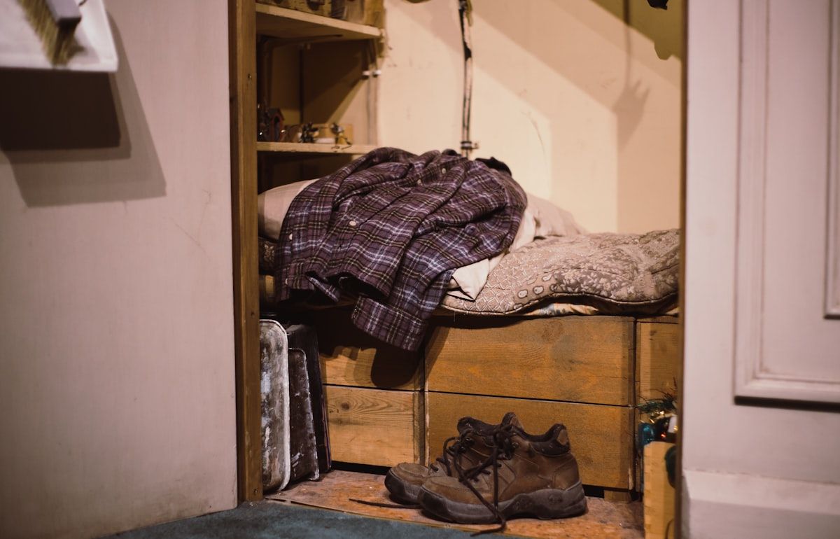 A walk-in closet divided into clear zones, with frequently worn jackets and shoes placed closest to the entrance, folded items stacked on labeled-looking bins and shelves, accessories grouped in trays and drawers, and seasonal storage in higher compartments, all arranged to show a functional daily dressing path.