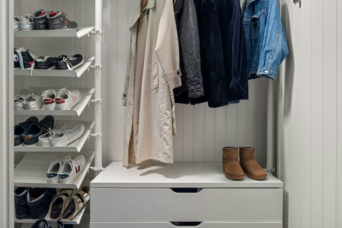 A deep closet section with one or two pull-out shoe trays extended outward on slides, revealing multiple pairs of shoes arranged side by side in the tray while darker unused space remains behind it, showing how the movable shelves bring the shoes into easy reach.