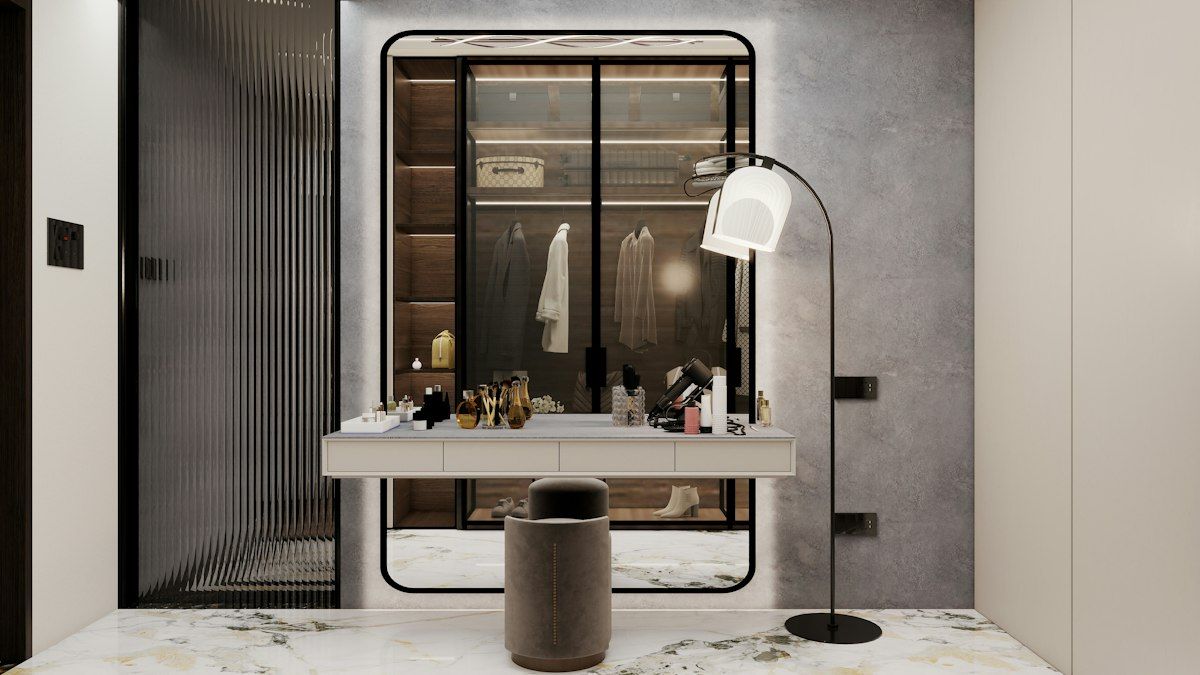 A large walk-in closet with a central island of drawers, a cushioned bench by the wall, neatly arranged shoe shelves, hanging bags on hooks, and a vanity area with a mirror and tray storage for accessories